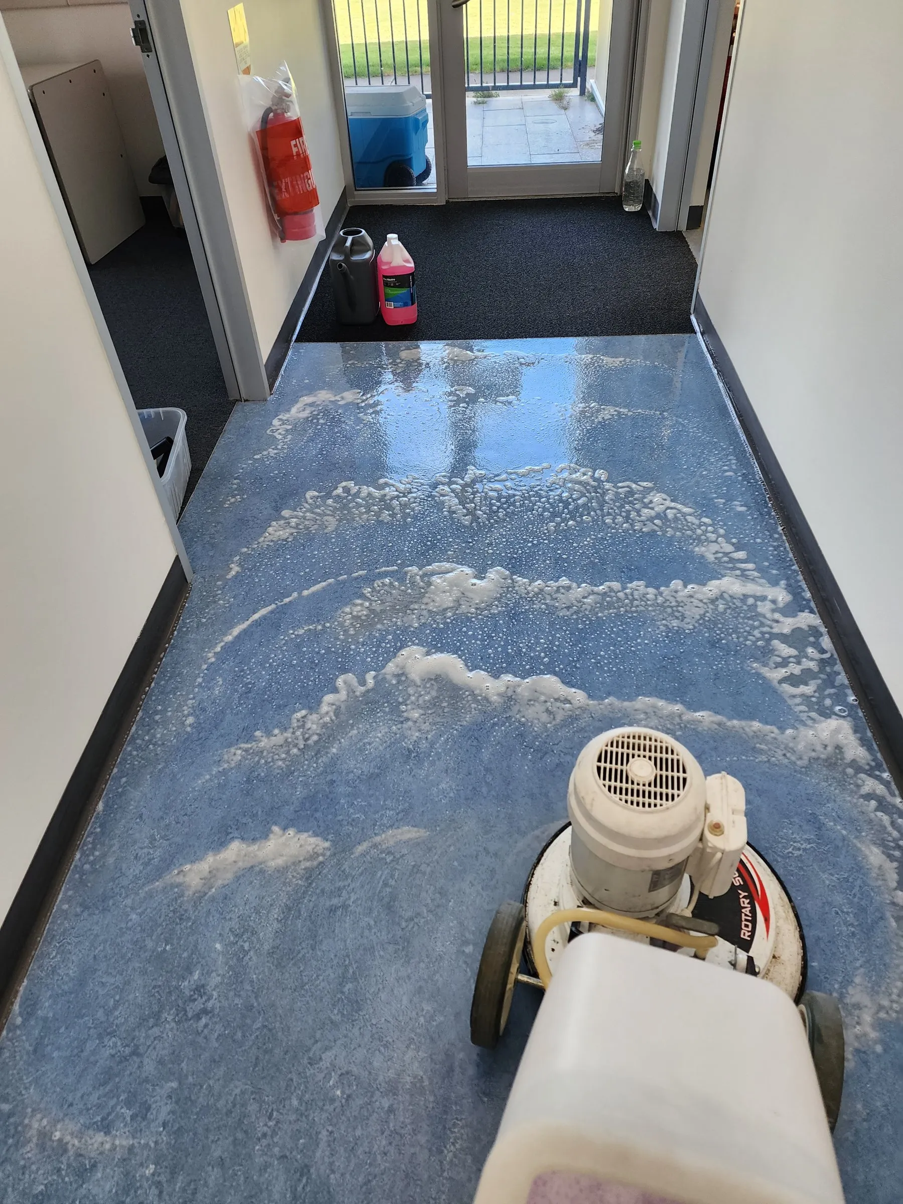 Floor machine working on a blue vinyl floor