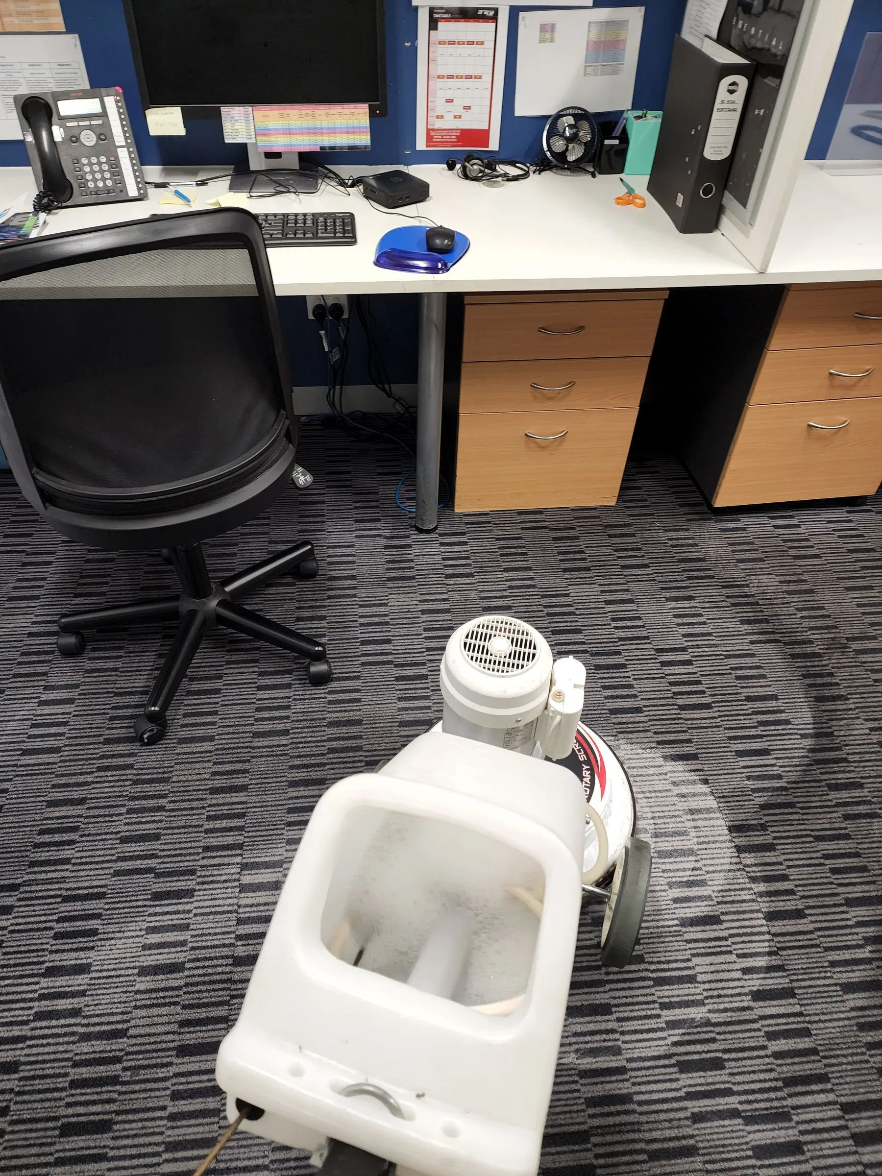 Extraction machine on office carpet tiles beneath desks