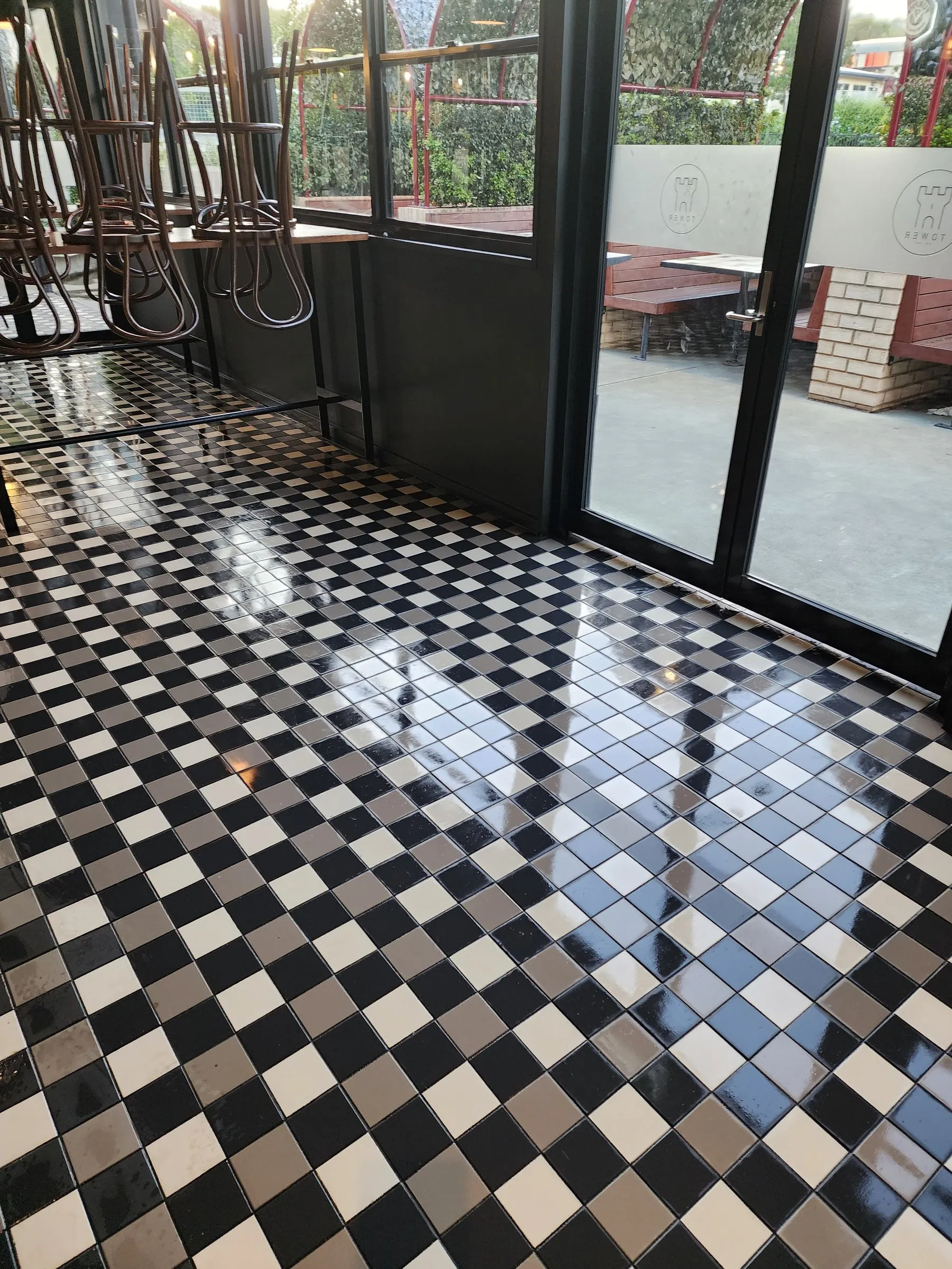 Checkerboard tile entry with a wet-look gloss and glass doors