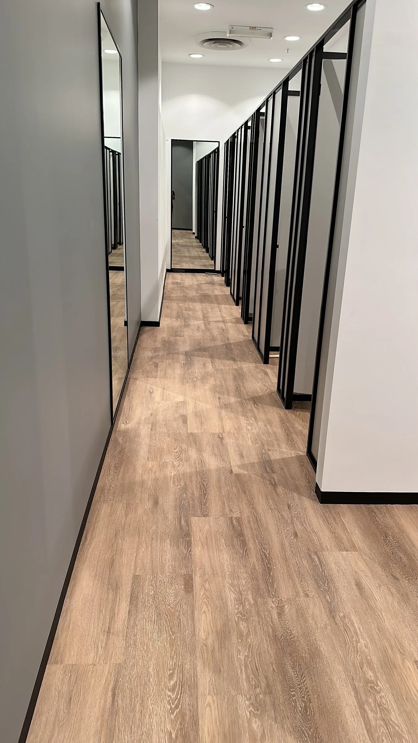 Long corridor of glass-walled offices with a timber floor