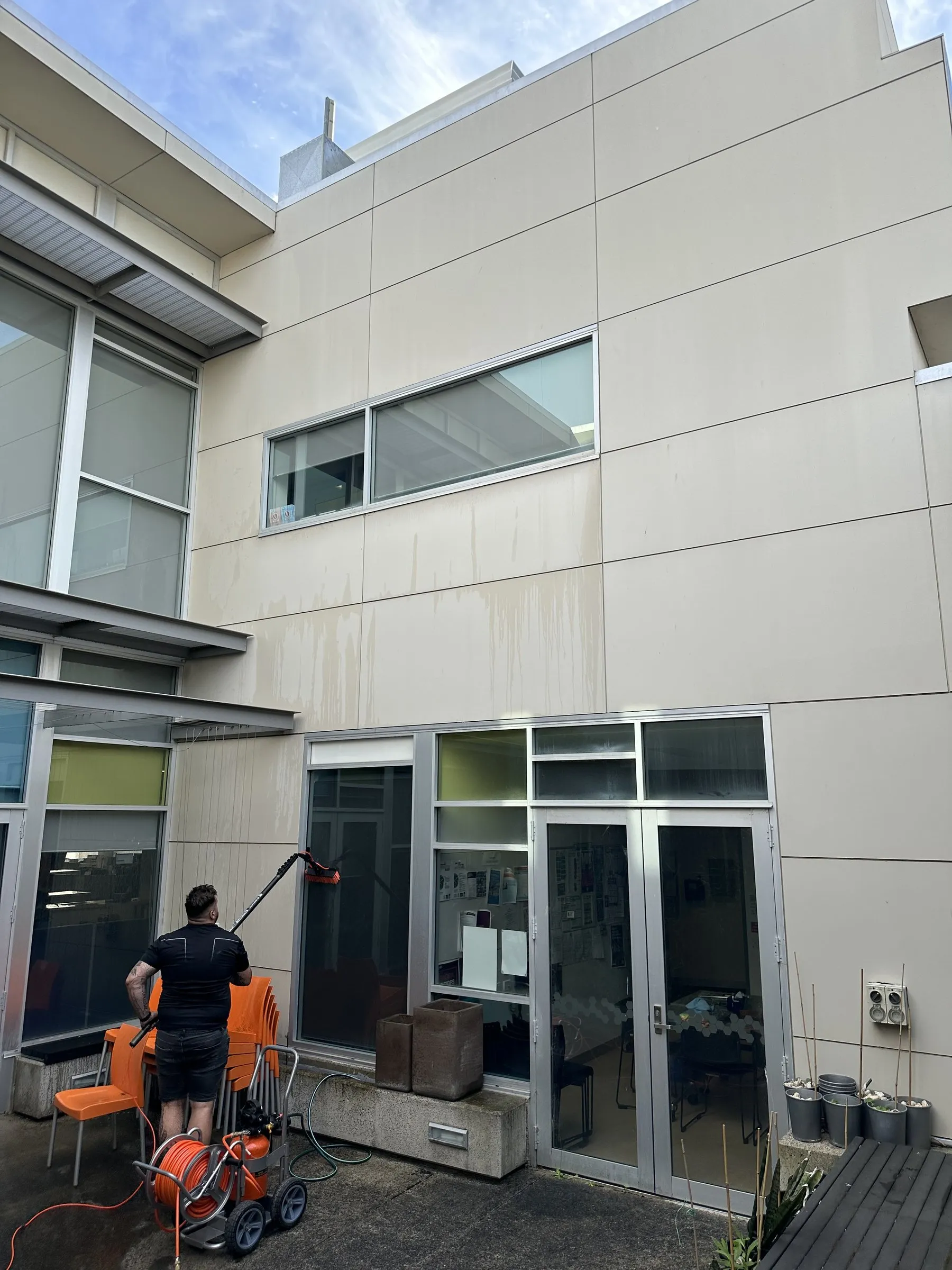 Technician cleaning the ground-floor glazing of a two-storey building