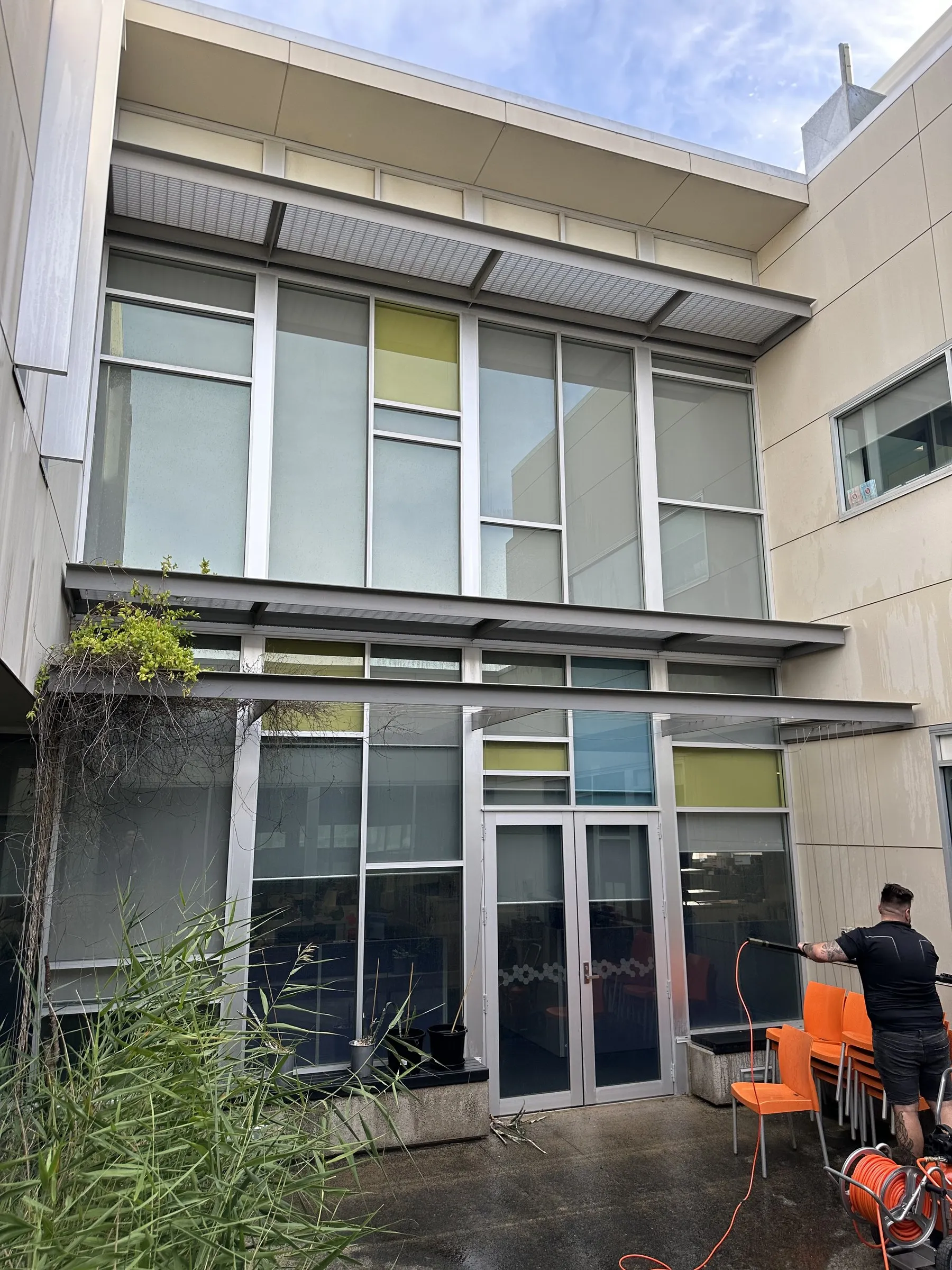 Technician cleaning the ground-floor glazing of a two-storey office