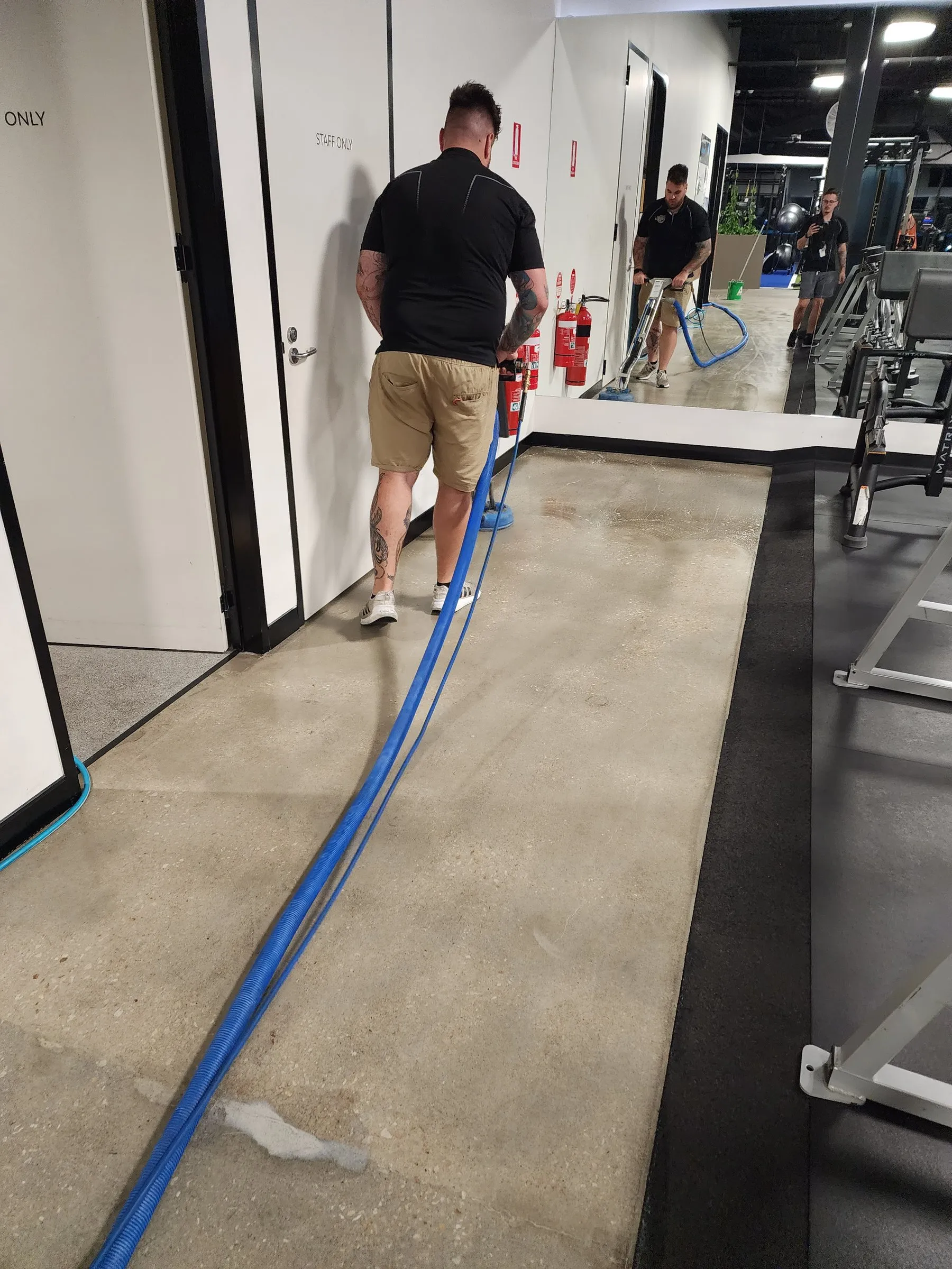 Technicians hosing a polished concrete corridor