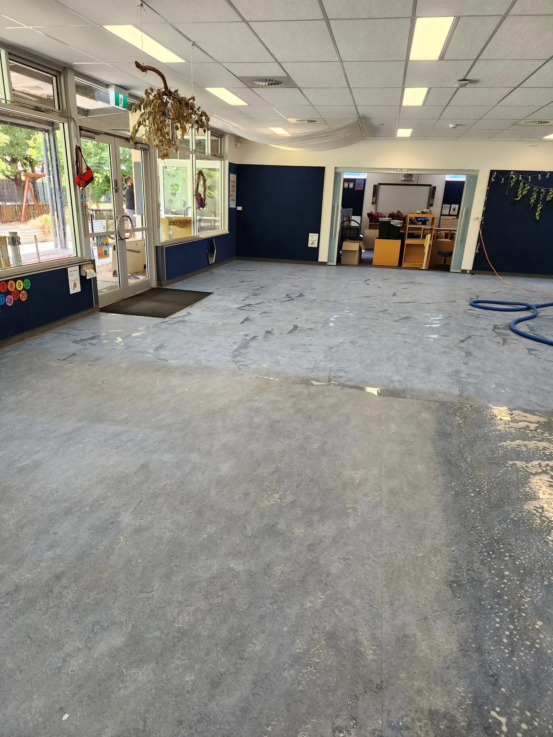 Wide room with a freshly scrubbed blue-grey vinyl floor, still wet