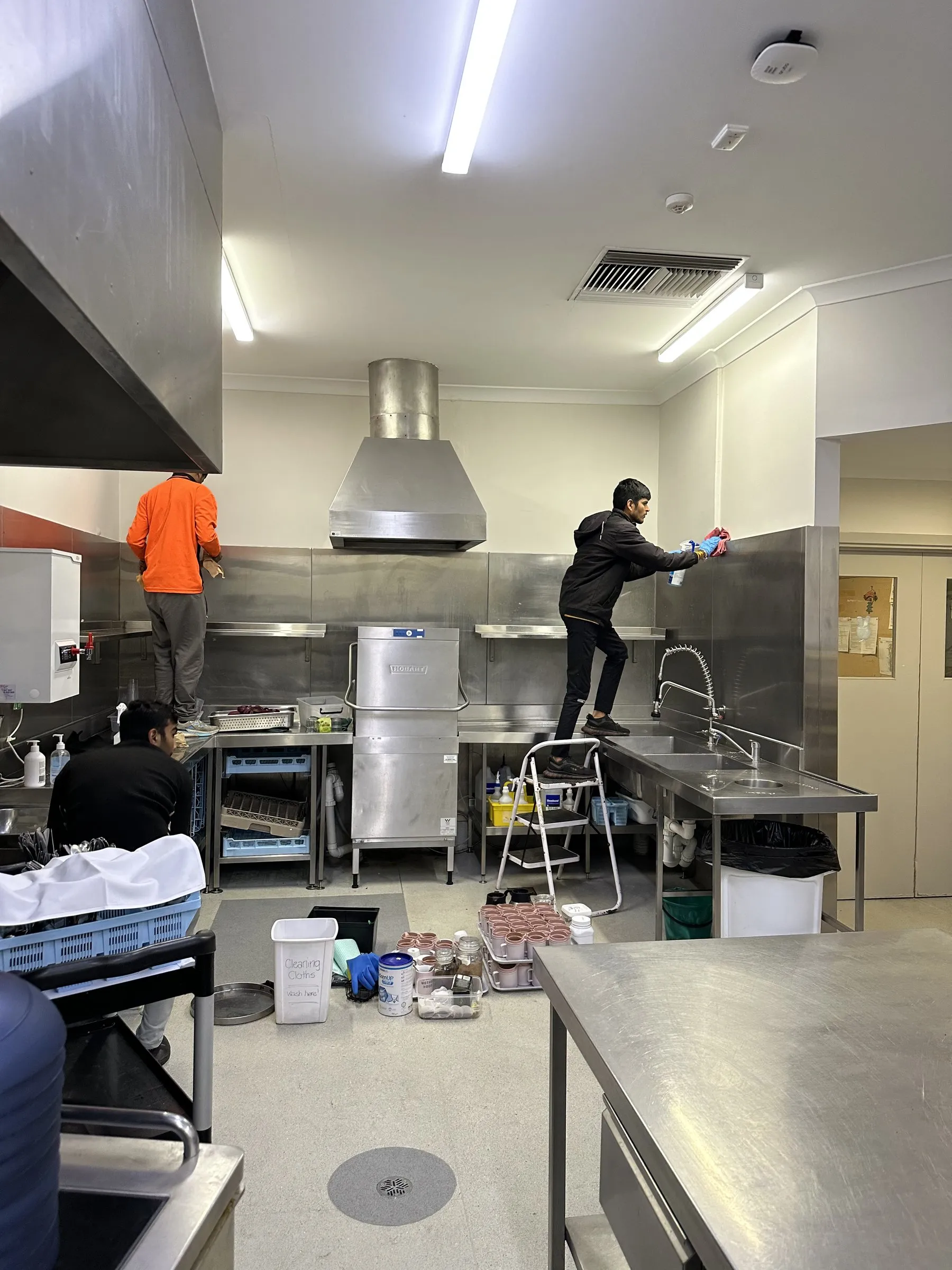 Commercial kitchen deep clean, one person on a ladder at the canopy
