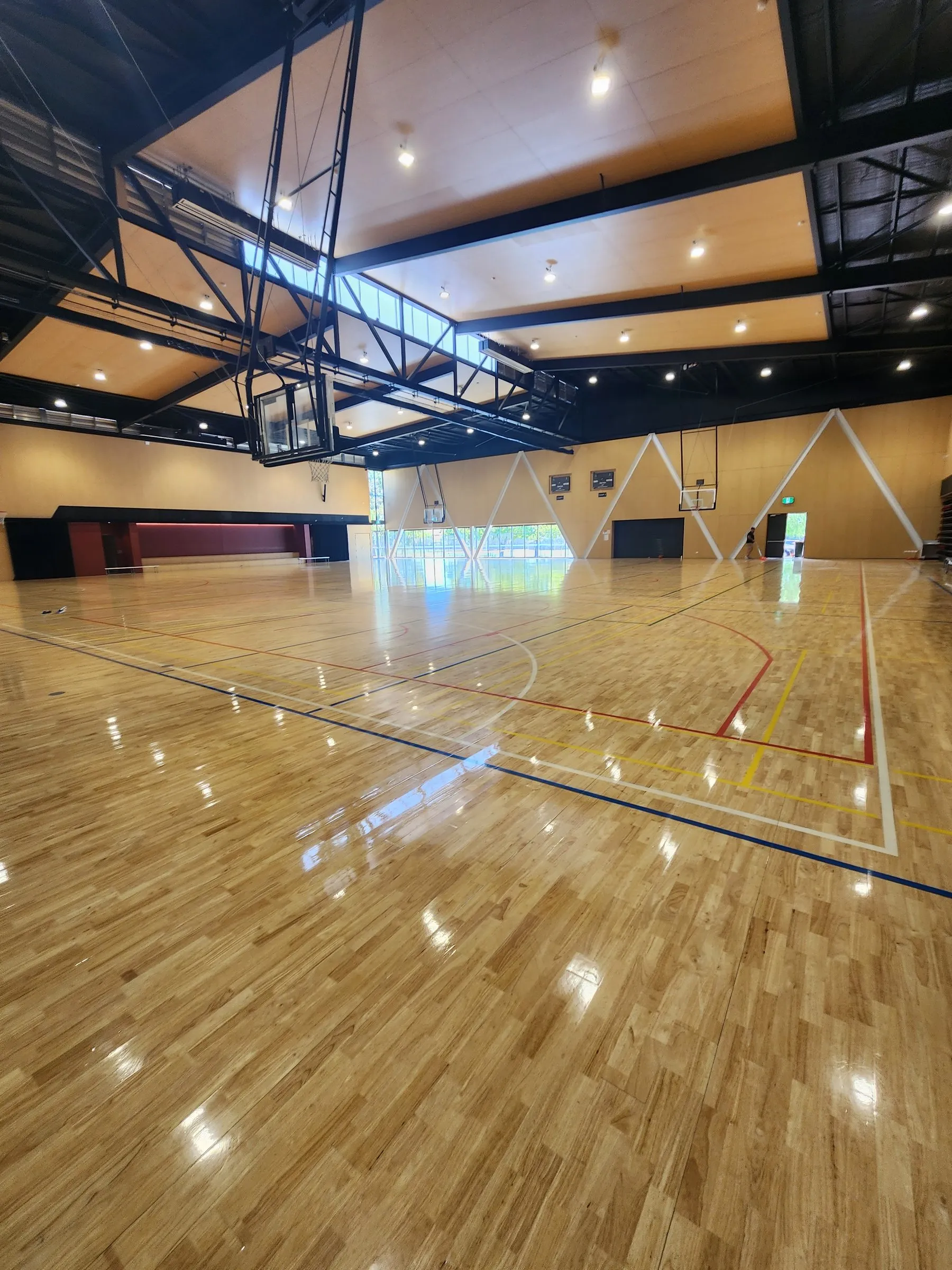 Timber basketball-court floor in a hall with a high-gloss finish