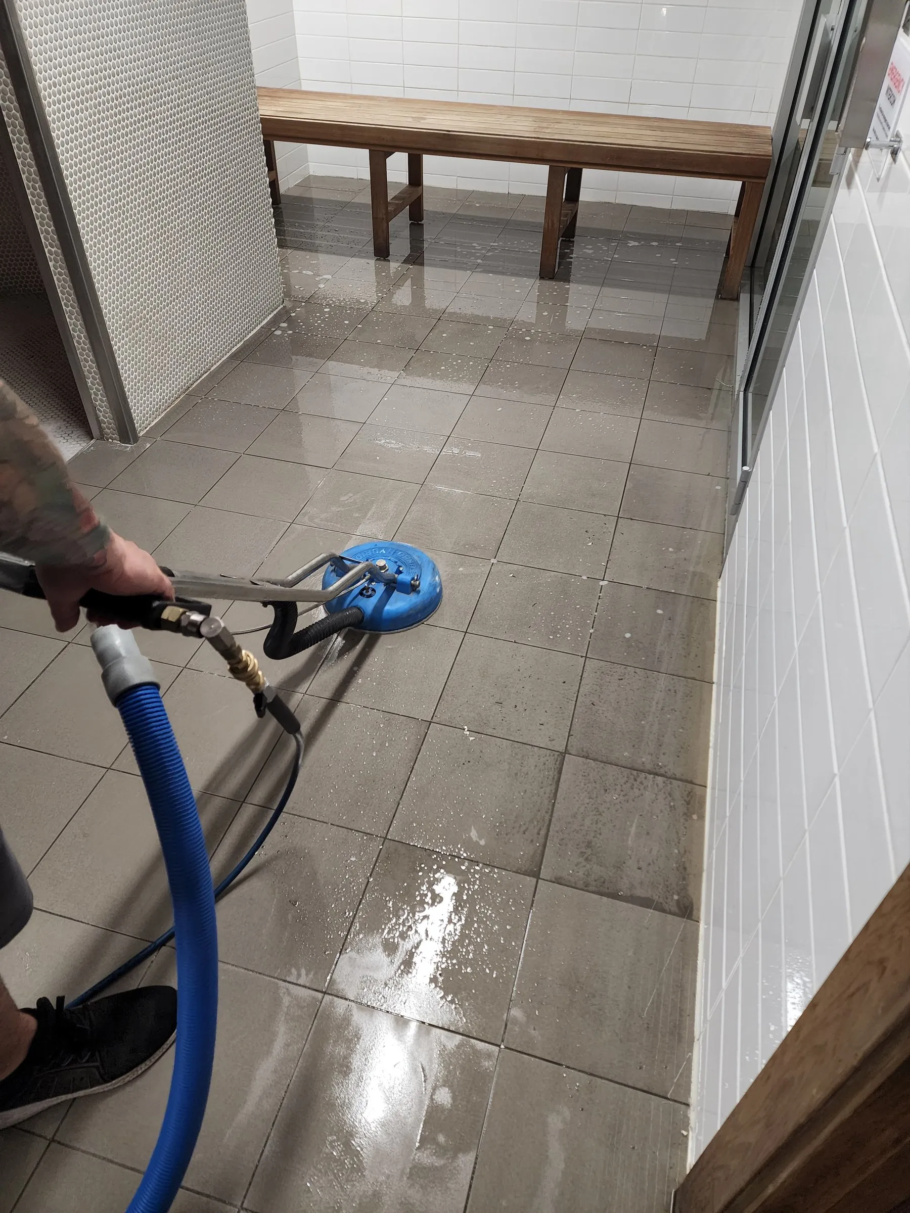 Spinner wand scrubbing grey tiles in a corridor