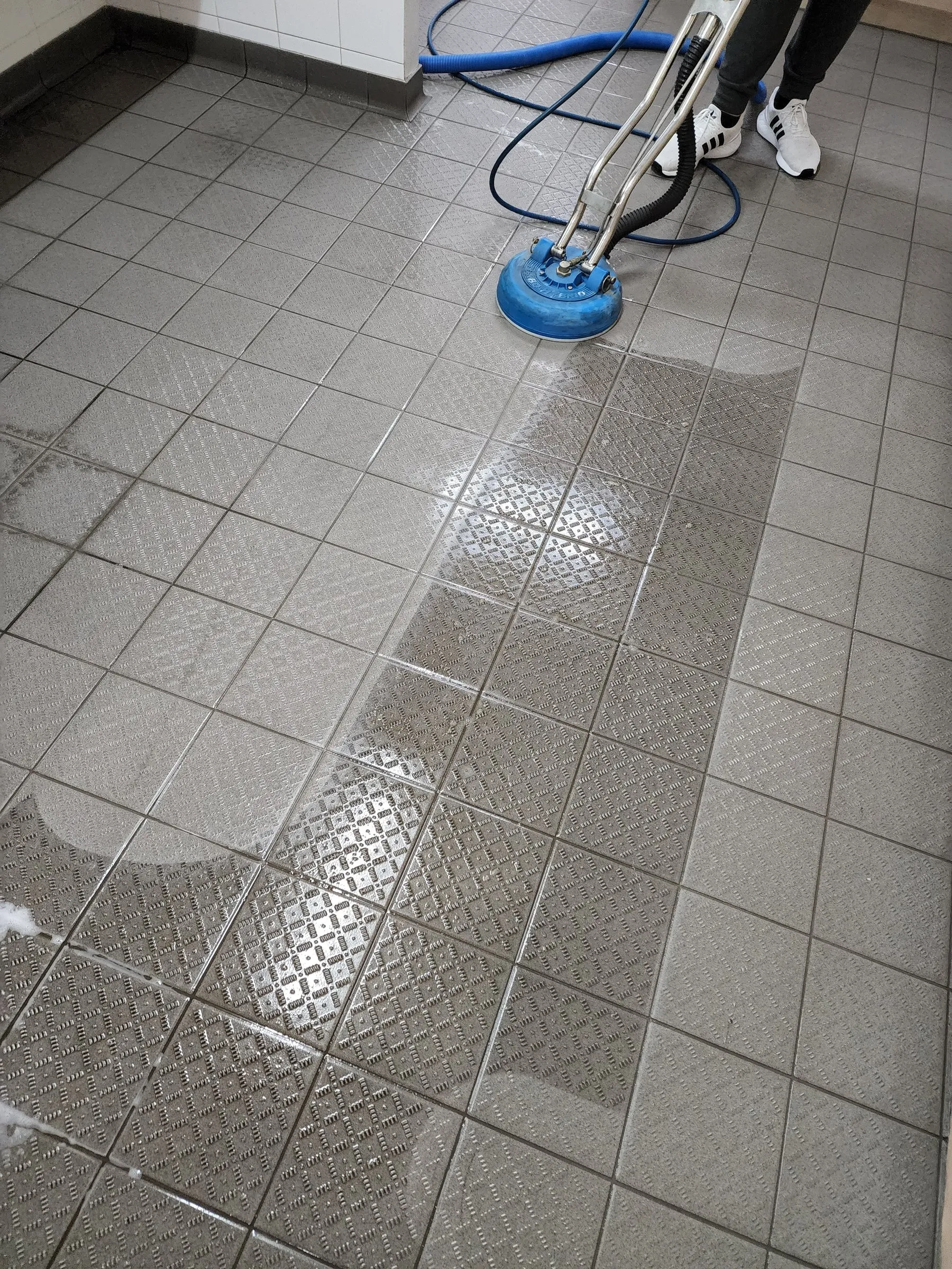Spinner wand cleaning grey textured floor tiles